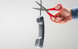Openreach PSTN switch-off concept: person with scissors cutting a telephone cable.