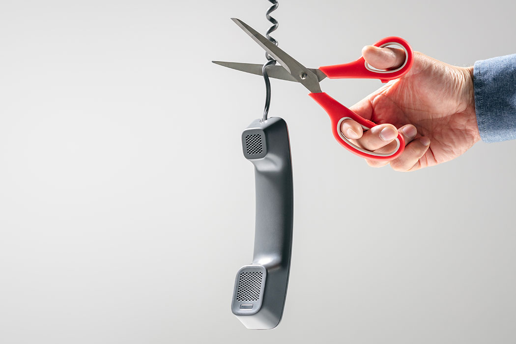 Openreach PSTN switch-off concept: person with scissors cutting a telephone cable.